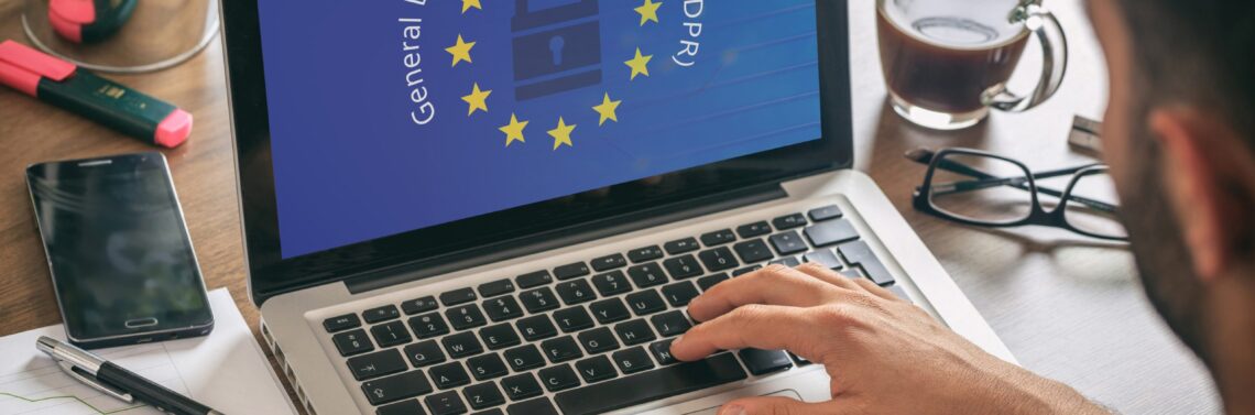 Manos sobre un teclado de laptop y el logo de GDPR en la pantalla