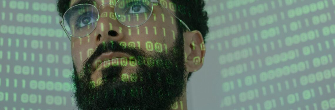 Man with binary code projected on his face because a company opted to hire ethical hacking - hacking ético