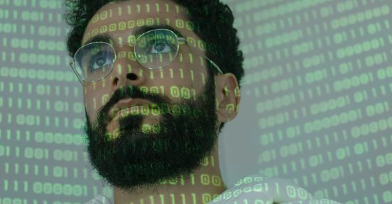 Man with binary code projected on his face because a company opted to hire ethical hacking - hacking ético