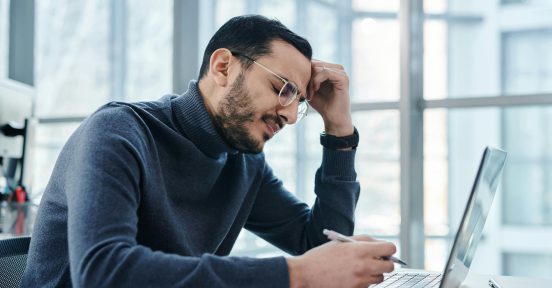 Men in front of a computer trying to use AI in cybersecurity for an enterprise.